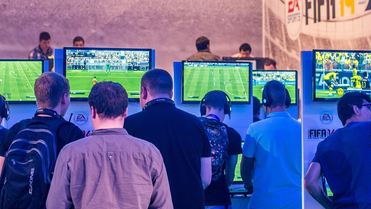 Rows of players at FIFA 14 game stations on the EA stand at Gamescom 2013