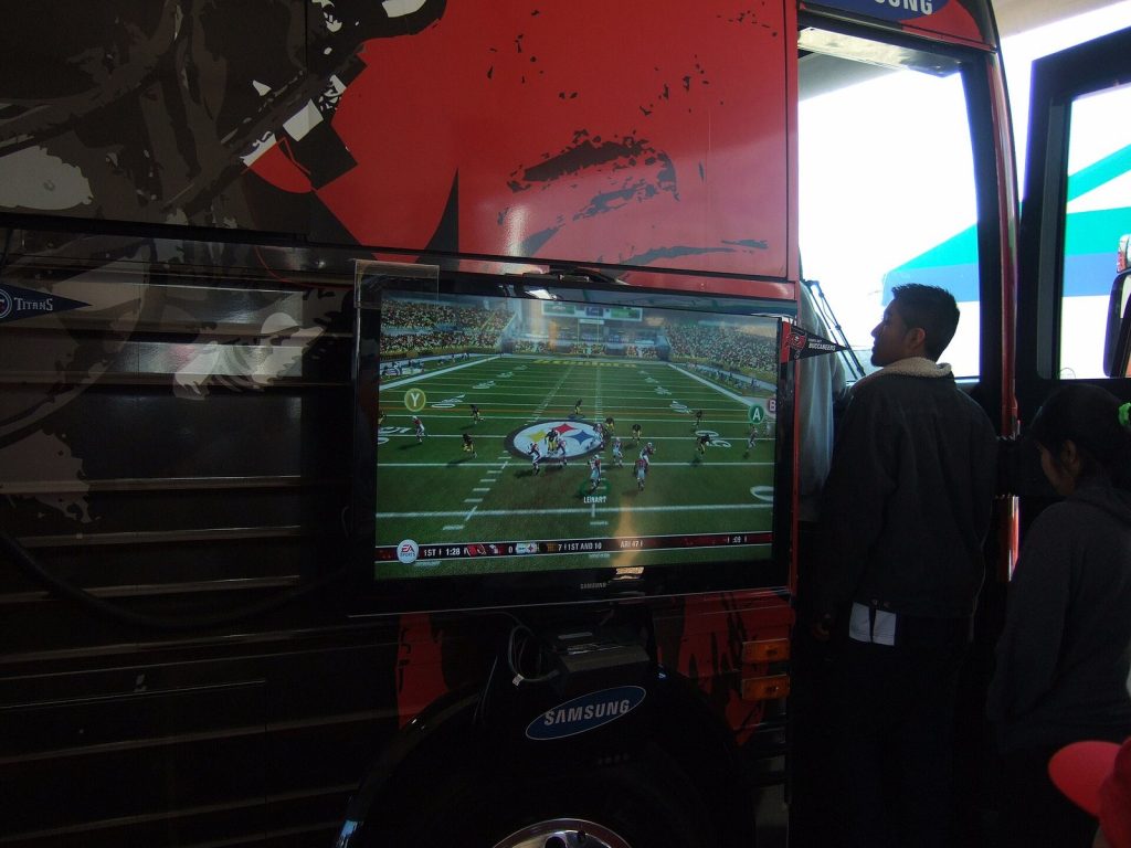 Players competing in a Madden NFL video game tournament in front of screens